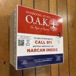 photo of overdose aid kit (OAK), a red white and blue metal box, hanging on wall in office lobby.